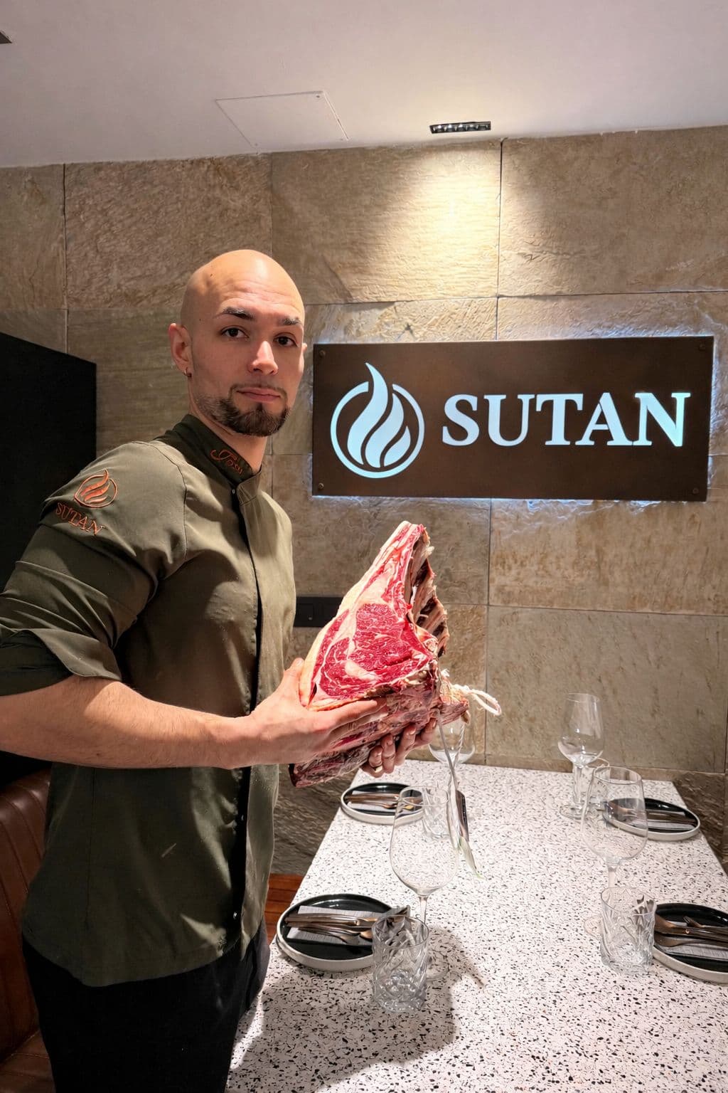 Chef de Sutan Cook sosteniendo una chuleta de vaca gallega